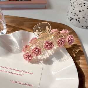 Detail of pink resin rose hair claw clip resting on an elegant white ceramic tray