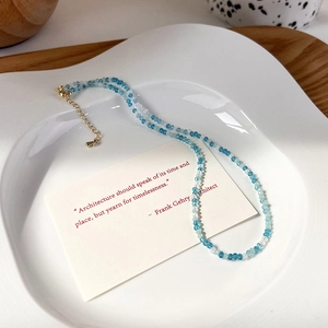 Dettaglio della collana di perline di cristallo blu e bianco su un vassoio decorativo in ceramica