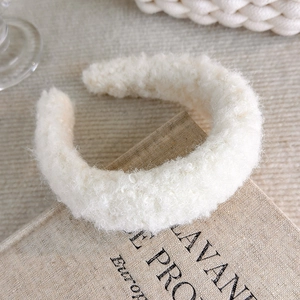Close-up of cream fuzzy headband on a book showing thick faux shearling texture