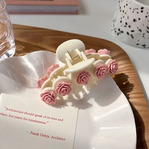 Detailed view of a creamy white hair claw clip with delicate pink resin roses
