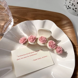 Detail of pink camellia hair claw clip with 3D floral accents on a shell-textured plate