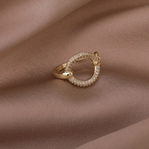 Macro shot of gold-plated ring with pavé-set zircons on dark brown silk background