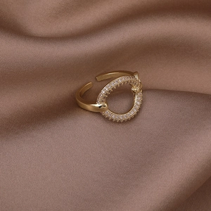 Macro detail of gold-plated ring with shimmering paved zircons on dark silk fabric