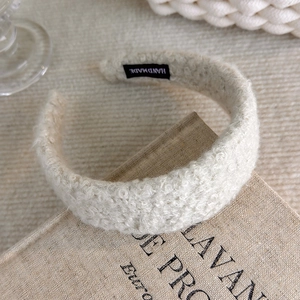 Close-up of a white plush headband with handmade woven label on soft textured fabric
