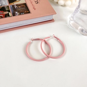 Detailansicht großer rosa mattierter Kreolen auf einem minimalistischen Hintergrund