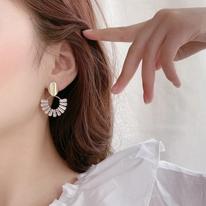 Elegant gold fan-shaped drop earrings with oval crystal gems worn by a model