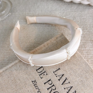 Detail showing elegant champagne satin headband with decorative pearls and beads