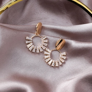 Macro shot of gold geometric earrings with rectangle crystals on pink silk fabric