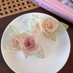 Detailweergave van organza roos haarspelden met delicate goudgeborduurde bladeren