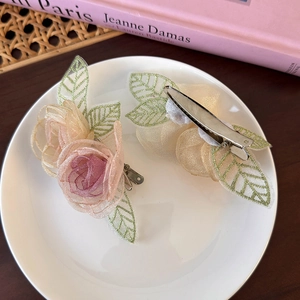 Detail van handgemaakte organza rozen haarclips in roze en champagne met geborduurde bladeren