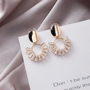 Detailed view of gold geometric earrings with rectangle crystals on silk background