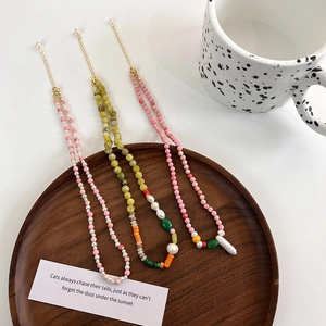 Three handmade freshwater pearl and natural stone necklaces in a rustic wooden bowl