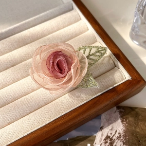 Detailopname van roze organza bloembroche met groen geborduurde bladeren op fluweel