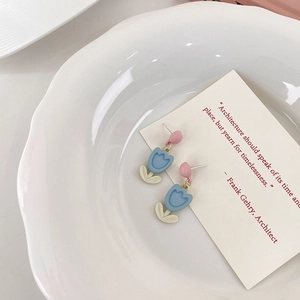 Dettaglio di orecchini a forma di tulipano opachi in rosa e blu su piatto di ceramica