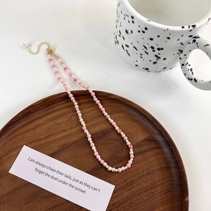 Detail of handmade freshwater pearl and pink marble bead necklace on wooden tray