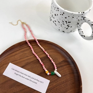 Close-up of handmade pink stone beads with a large baroque pearl on a wooden tray