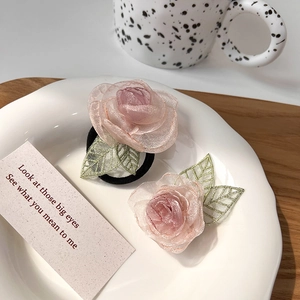 Detailopname van roze organza bloem haarelastiekje en geborduurde groene bladeren