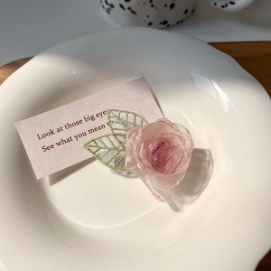 Detail van roze organza rozen haarklem met geborduurde groene bladeren op wit bordje