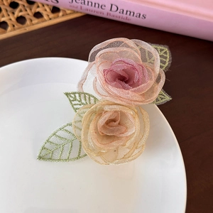 Detail van roze en crème mesh camelia bloemen met geborduurde groene bladeren