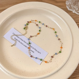 Nahaufnahme der bunten Halskette mit transparenten Würfelperlen und goldener Kette