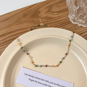 Detail einer bunten quadratischen Perlenkette auf Goldkette in einer Keramikschale