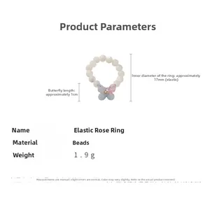 Détail macro d'une bague élastique en perles avec pendentif papillon en résine dégradée