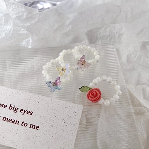 Ensemble de bagues perlées élastiques avec papillons colorés et rose rouge sur plateau