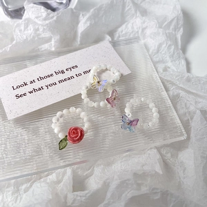 Détail des bagues en perles avec roses et papillons aux reflets opale scintillants