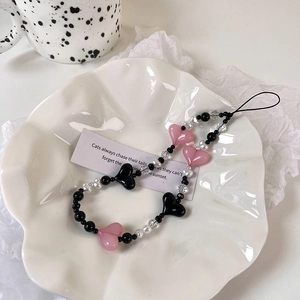 Close-up of pink heart-shaped beads and pearls on a stylish beaded phone strap charm