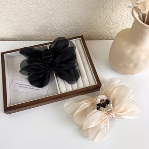 Close-up of large champagne and black tulle bow hair claws on a wooden tray