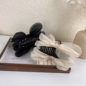 Detail of elegant black and champagne organza bow hair claws on a wooden display tray