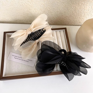 Macro detail of large layered organza bow hair claw clips in beige and black colors