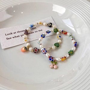 Détail de bracelets perlés à la main avec perles d'eau douce et breloques de fruits