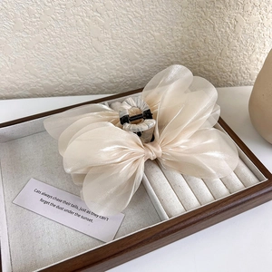Detail of elegant cream organza bow hair claw clip on a jewelry display tray