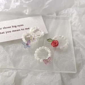 Ensemble de trois bagues en perles avec papillons en opale et accents floraux roses