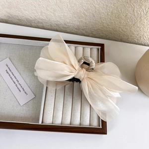 Close-up of cream organza bow hair claw clip placed on a wooden jewelry box