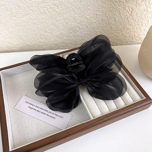 Detail of elegant black mesh bow hair claw clip on a vintage jewelry display tray