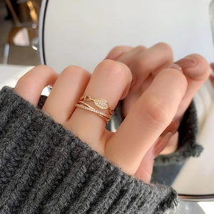 Gros plan d'une bague multicouche dorée avec zircons croisés sur une main avec miroir