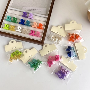 Set of four colorful matte cross mini hair claws in vibrant resin finishes with packaging