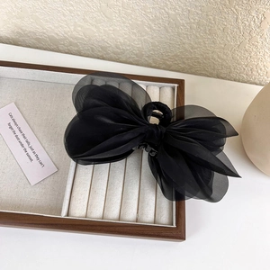 Detail of multi-layered black sheer fabric bow hair claw clip in a wooden box
