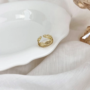 Gros plan détaillé d'une bague double couche dorée avec zircons sur soie blanche