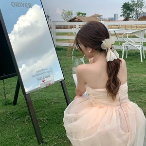 Elegant white chiffon bow hair claw with pearls worn by a model in a garden setting