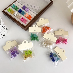 Set of colorful frosted criss-cross hair claw clips for women displayed in a wooden tray