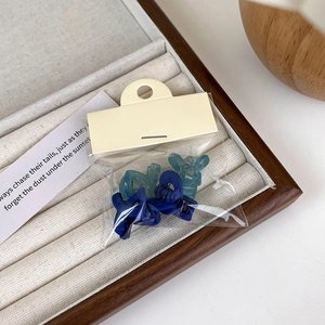 Close-up of matte dark blue and light cyan mini hair claws in clear packaging