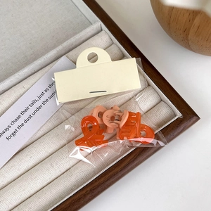Detail shot of mini matte cross hair claws in orange and pink on a beige display tray