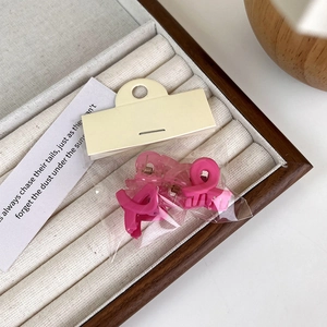 Detail of mini matte hair claws in pink and rose red packaged in a clear retail polybag