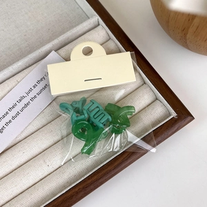 Close-up of mini green matte hair claws with gold springs in a velvet jewelry tray