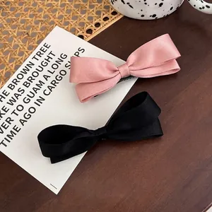 Set aus rosa und schwarzen Satin-Haarspangen mit Schleifen auf einem Holztisch im Korea-Stil