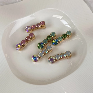 Close-up of sparkling colorful rhinestone hair clips on a white ceramic plate