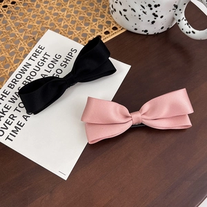 Set aus zwei niedlichen rosa und schwarzen Doppelschleifen-Haarspangen auf Holztisch